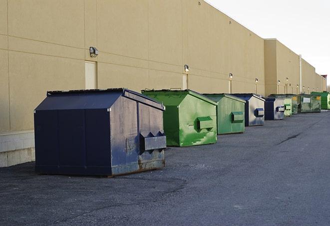 a group of dumpsters lined up along the street ready for use in a large-scale construction project in Allston, MA